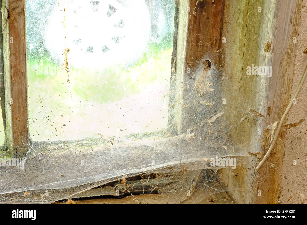 Gros plan d'une vieille fenêtre avec des toiles et de la saleté dans une maison abandonnée. Zoomez sur le cadre en bois, la texture et la conception d'une fenêtre en bois désordonné avec des détails macro d'une surface poussiéreuse et sale Banque D'Images