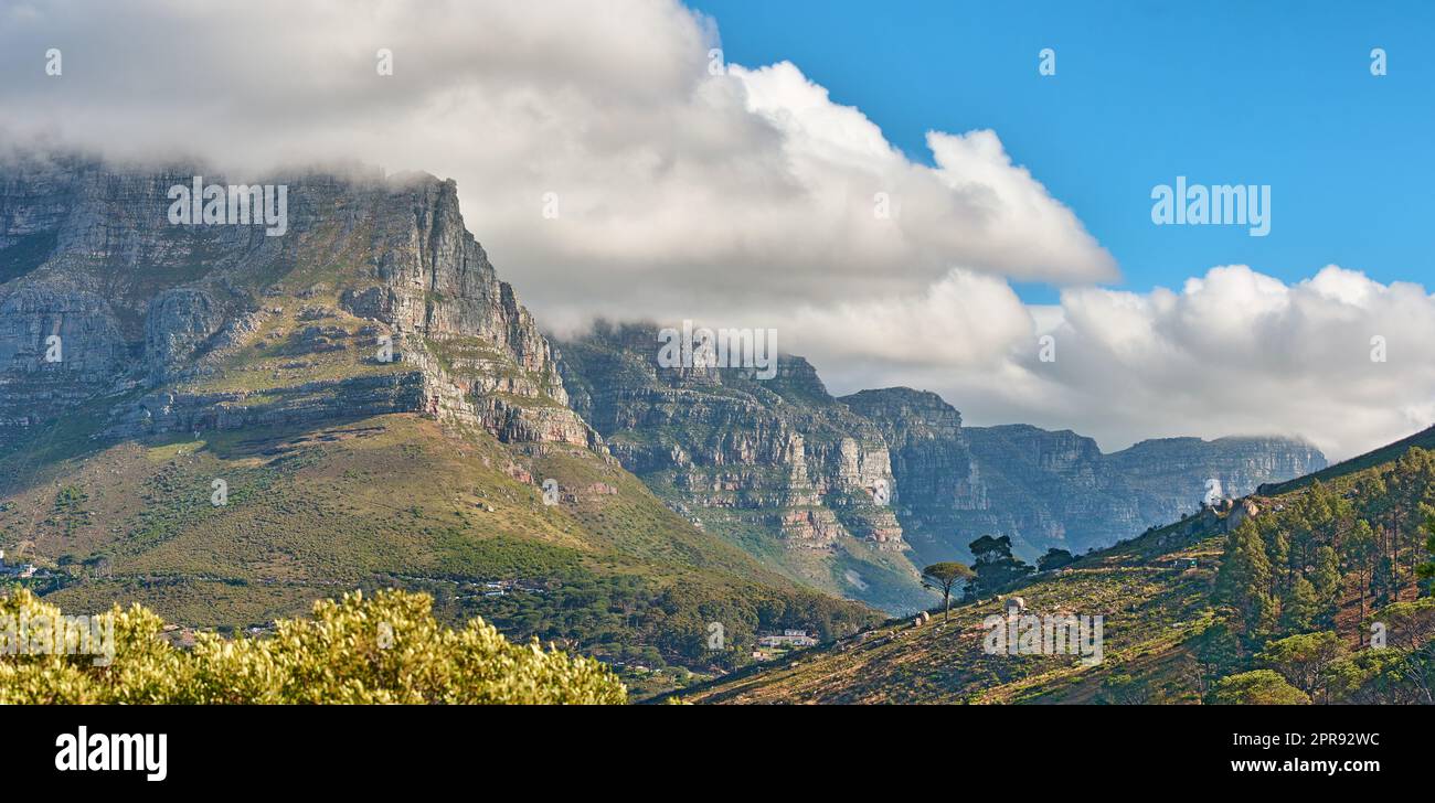 Vue panoramique sur une montagne avec des nuages qui se roulent dans un ciel bleu en été. CopySpace, vue panoramique sur un environnement naturel à la campagne. Paysage de collines et de nature Banque D'Images