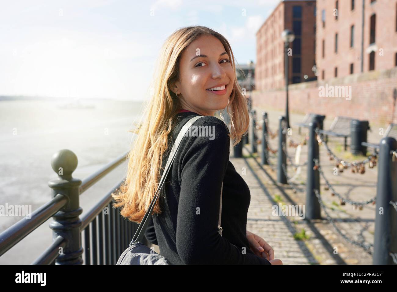 Portrait de la belle femme tourne et souriant à la caméra marchant sur la promenade de Liverpool au coucher du soleil, Royaume-Uni Banque D'Images