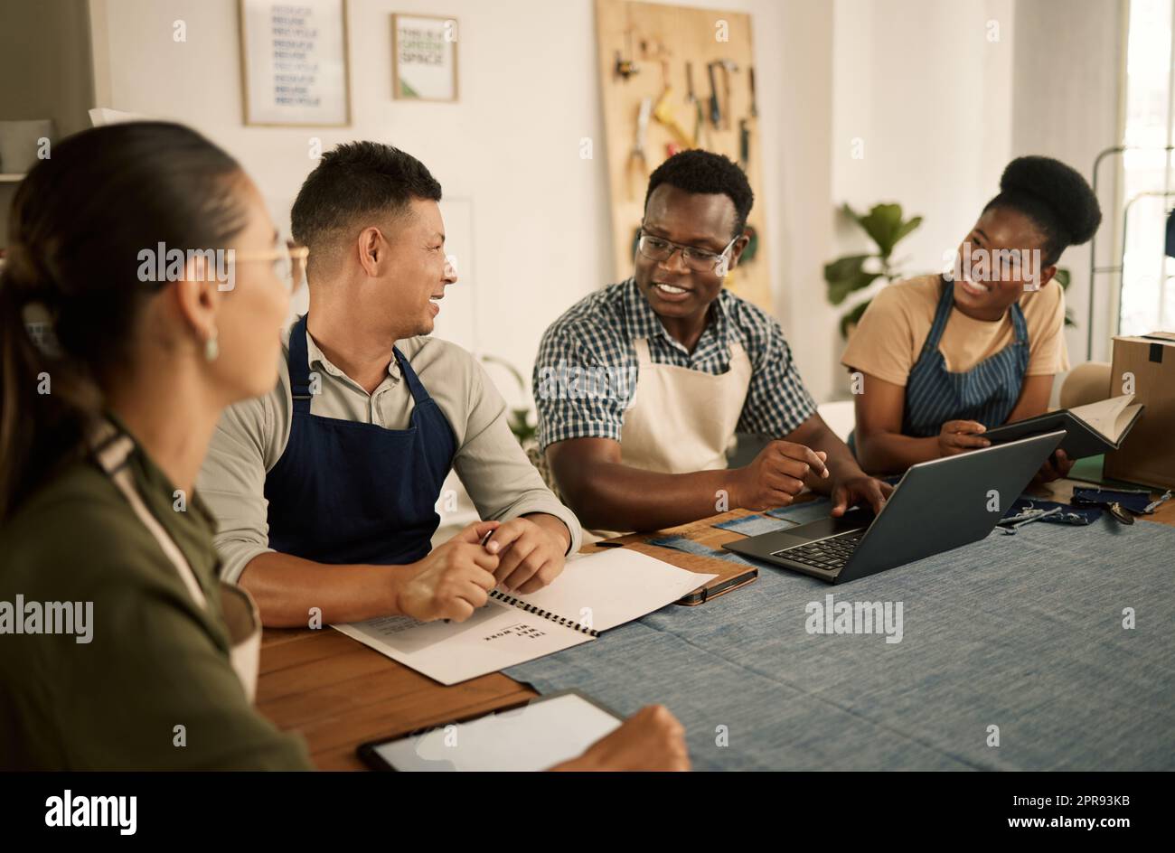 Un groupe de stylistes de vêtements et de mode travaillant ensemble en équipe, prenant des notes et faisant des recherches sur un ordinateur portable. Un groupe de professionnels enthousiastes, positifs et branchés qui collaborent. Banque D'Images