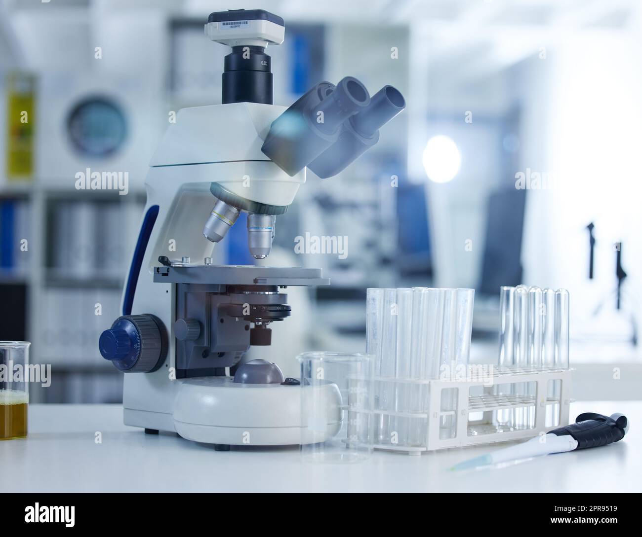 La recherche facilitée par la technologie. Un microscope et des lunettes sur une table dans un laboratoire. Banque D'Images