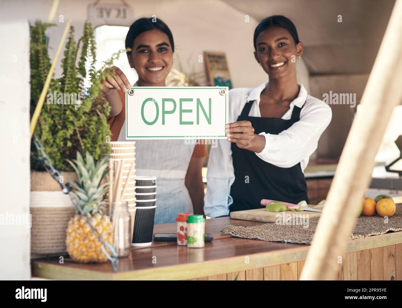 Toujours poursuivre vos objectifs. Deux jeunes femmes d'affaires tenant un panneau ouvert dans leur camion alimentaire. Banque D'Images