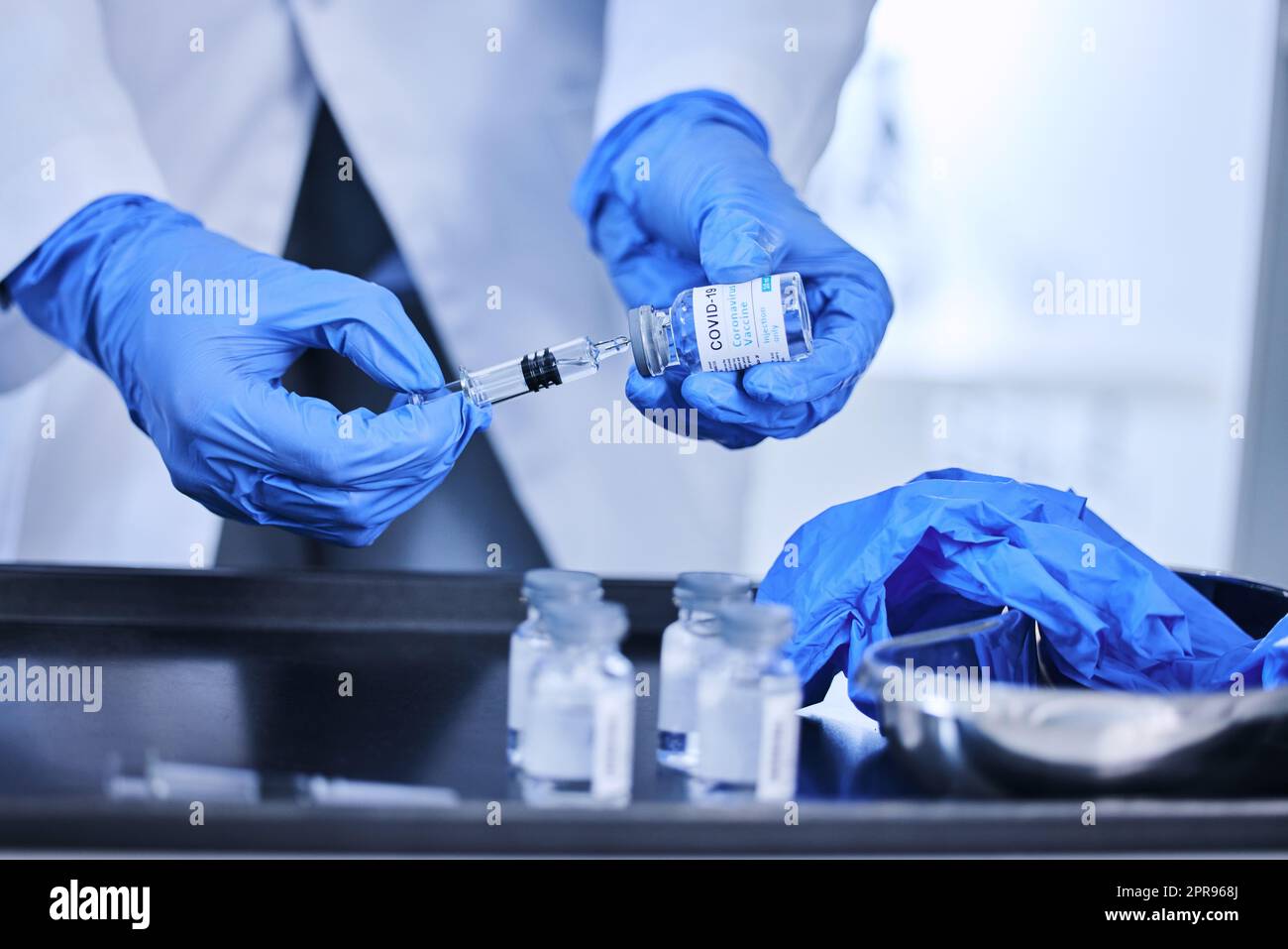 Un scientifique méconnaissable utilisant une seringue pour extraire le vaccin Covid 19 d'une bouteille en laboratoire. Banque D'Images