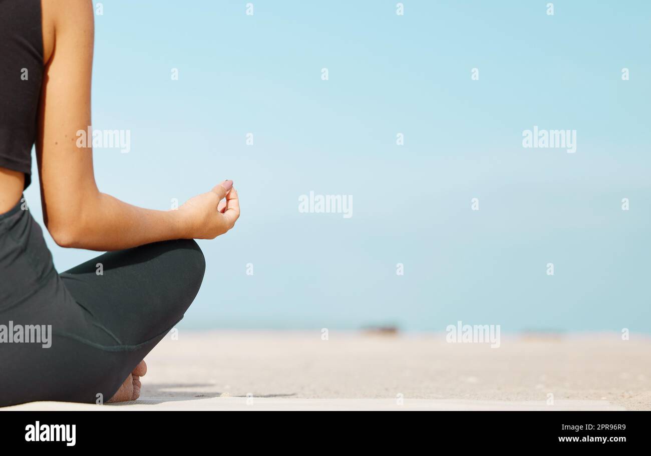 Restez calme et calme. Vue arrière d'une femme méconnue méditant à la plage. Banque D'Images