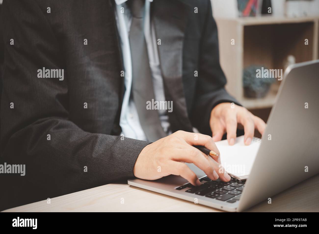 Homme personne utilisant un clavier ordinateur portable tenant un stylo et un livre sur le bureau. Banque D'Images
