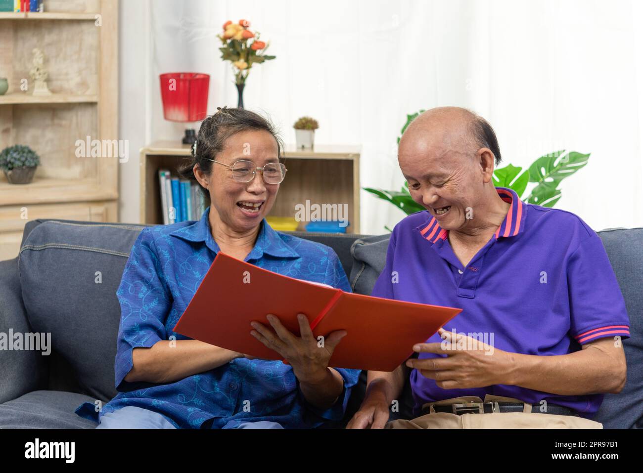 Couple asiatique senior parlant heureux de planifier le contrat de soins de santé d'assurance-retraite sur le canapé. Banque D'Images