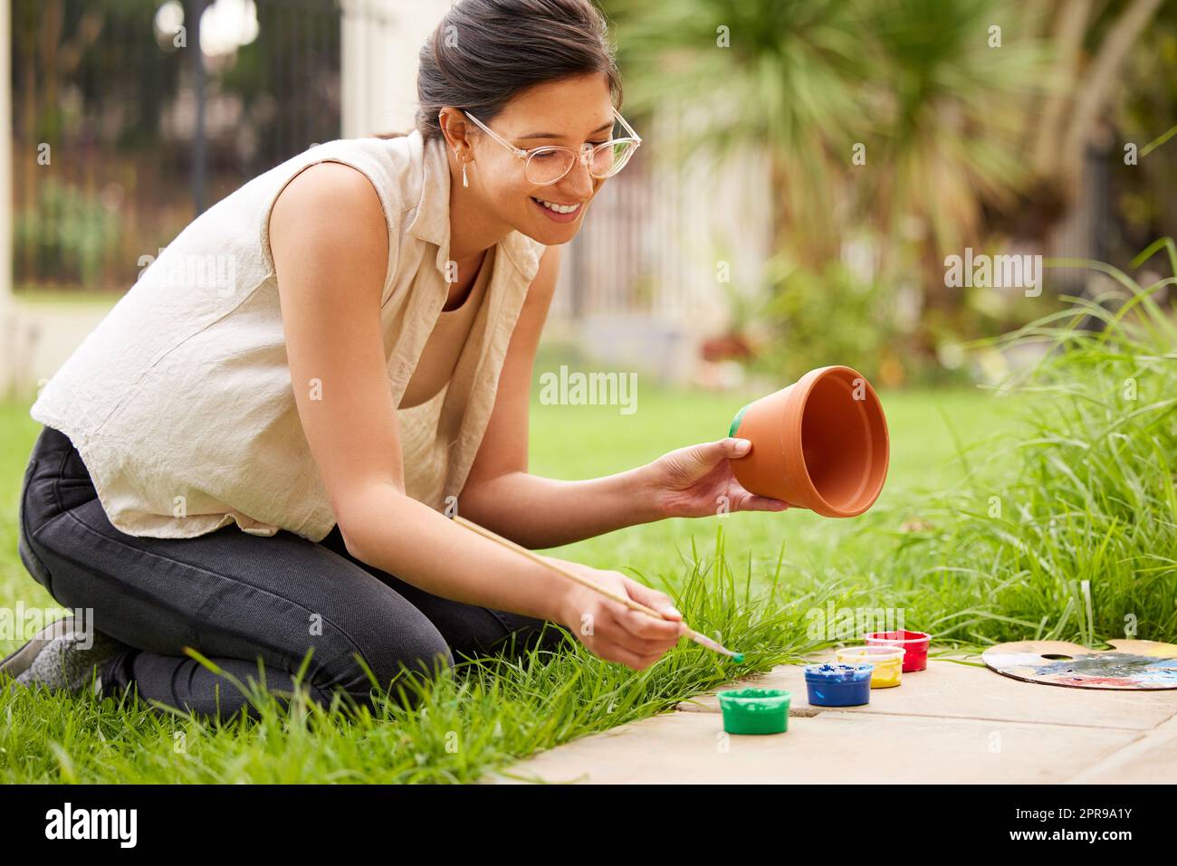 La créativité est juste de relier les choses. S jeune femme peint un pot dans le jardin à la maison. Banque D'Images