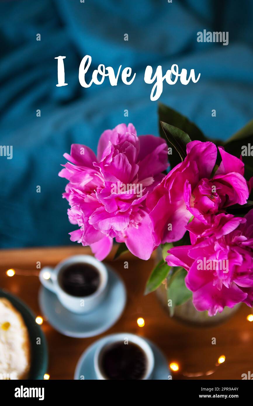 Beau cheesecake au vanille du matin, café, tasses bleues, pivoines roses dans un vase en verre. Inscription Je t'aime. Banque D'Images