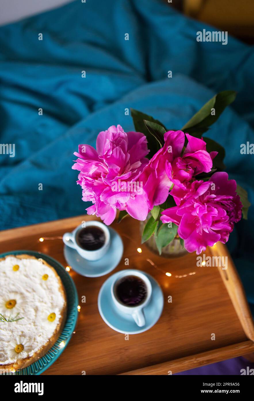 Beau cheesecake au vanille du matin, café, tasses bleues, pivoines roses dans un vase en verre. Banque D'Images