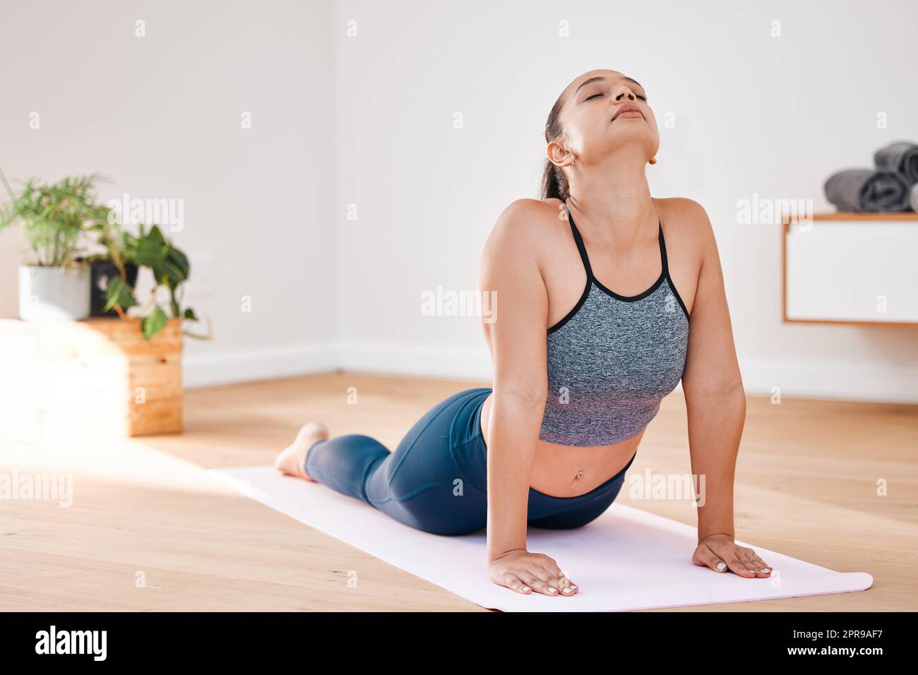 S'étirant de toute la négativité. Une jeune femme pratiquant le yoga à la maison. Banque D'Images