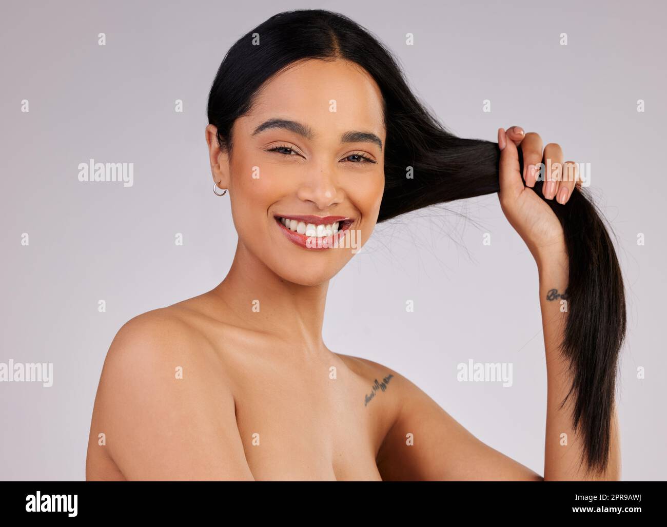 Des cheveux sains sont un sujet de sourire. Photo studio d'une belle jeune femme posant sur un fond gris. Banque D'Images