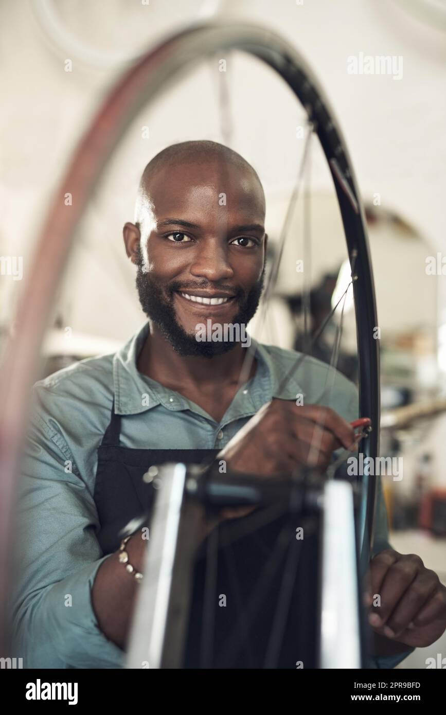 Je parle roi. Un beau jeune homme debout seul dans son magasin et répare une roue de vélo. Banque D'Images