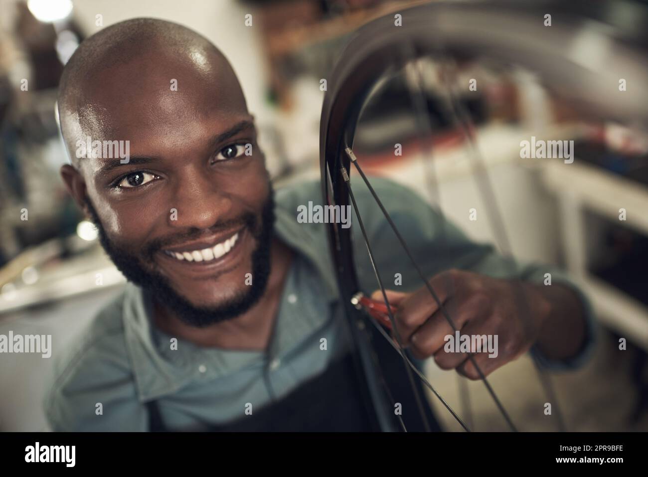 Nous fournissons un service de qualité ici. Un beau jeune homme debout seul dans son magasin et de réparer une roue de vélo. Banque D'Images