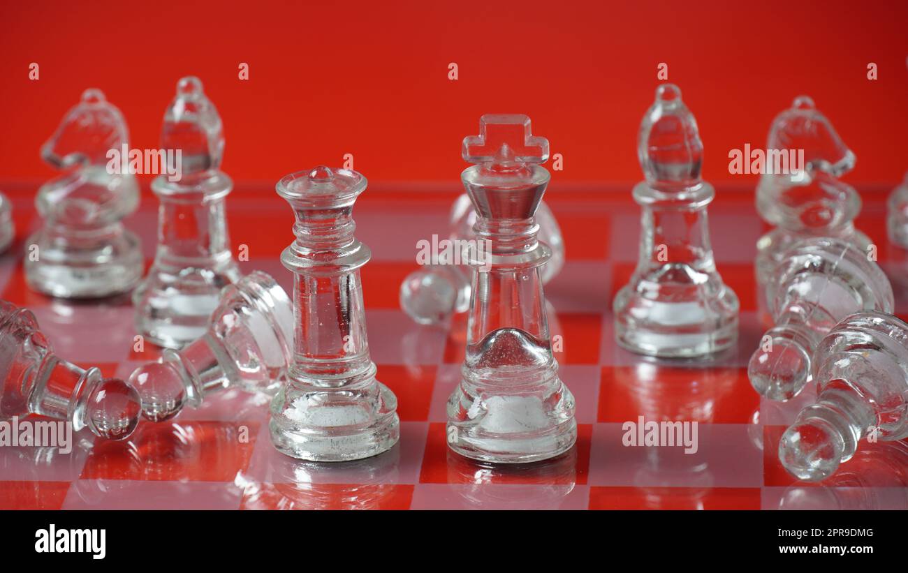 Figures d'échecs transparentes, sur la position de départ, sur le plateau d'échecs réfléchissant, ton rouge. Jeu de plateau d'échecs stratégiques Banque D'Images