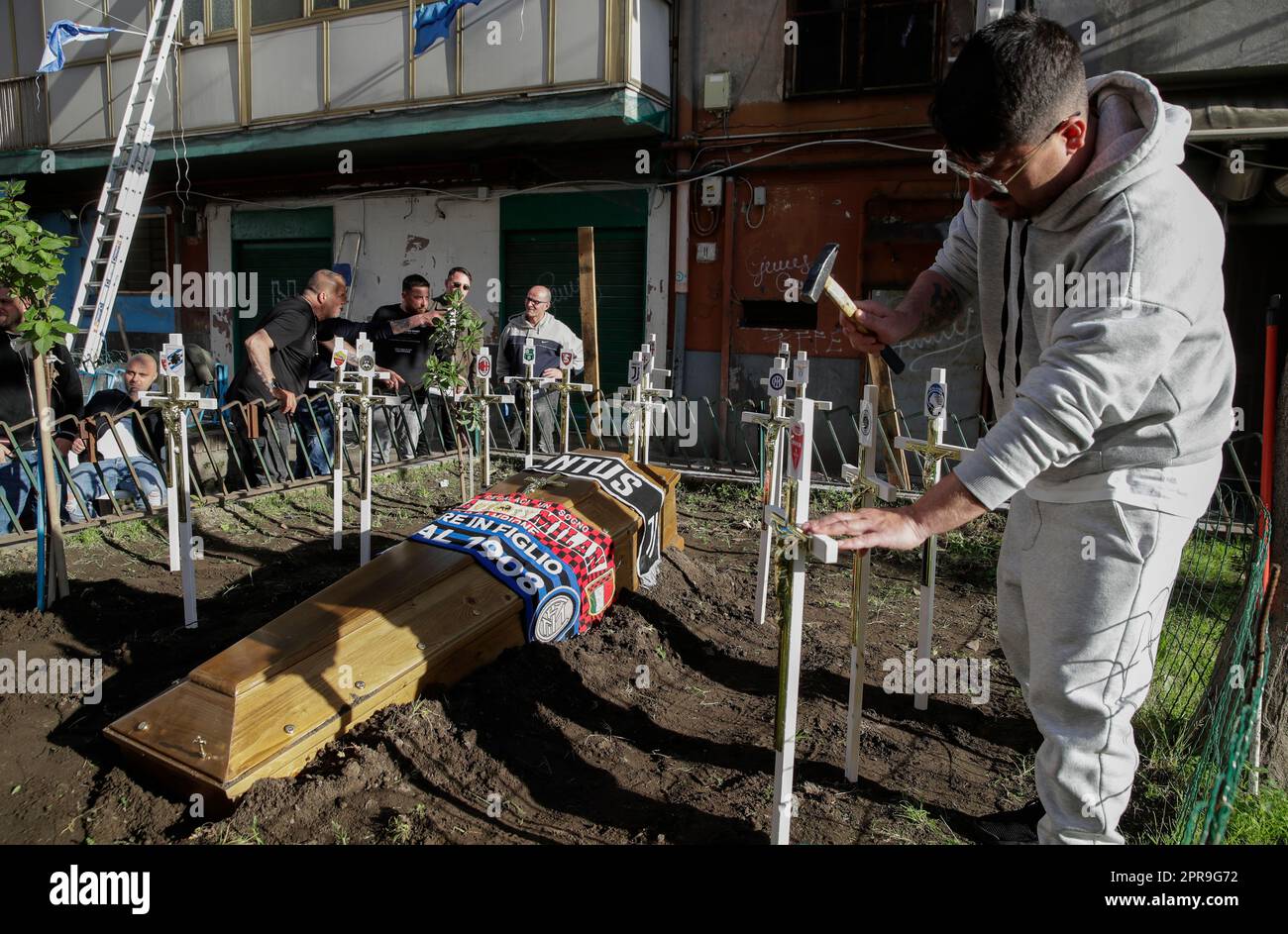 Naples, Italie. 26th avril 2023. Une plante de soutien croise avec les symboles de toutes les équipes italiennes Serie A football à côté d'une tombe factice pour un cercueil orné des foulards des équipes de football FC Inter, FC Juventus et AC Milan devant un club de fans de SSC Napoli. Alors que Napoli pourrait gagner la série Un championnat de football dès le dimanche prochain, les préparatifs pour les célébrations sont en plein essor dans la ville. Crédit : Agence photo indépendante/Alamy Live News Banque D'Images