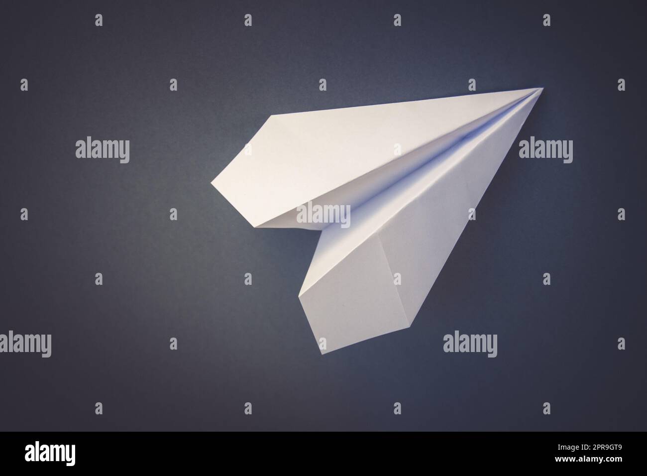 Avion de papier blanc origami isolé sur fond gris Banque D'Images