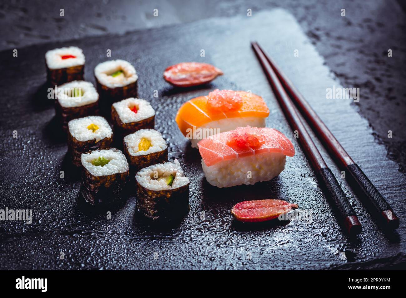 Assortiment de sushi végétaliens avec légumes, seitan, plante de Konjac, tofu comme substituts de poisson, avec le citron vert comme caviar sur noir Banque D'Images