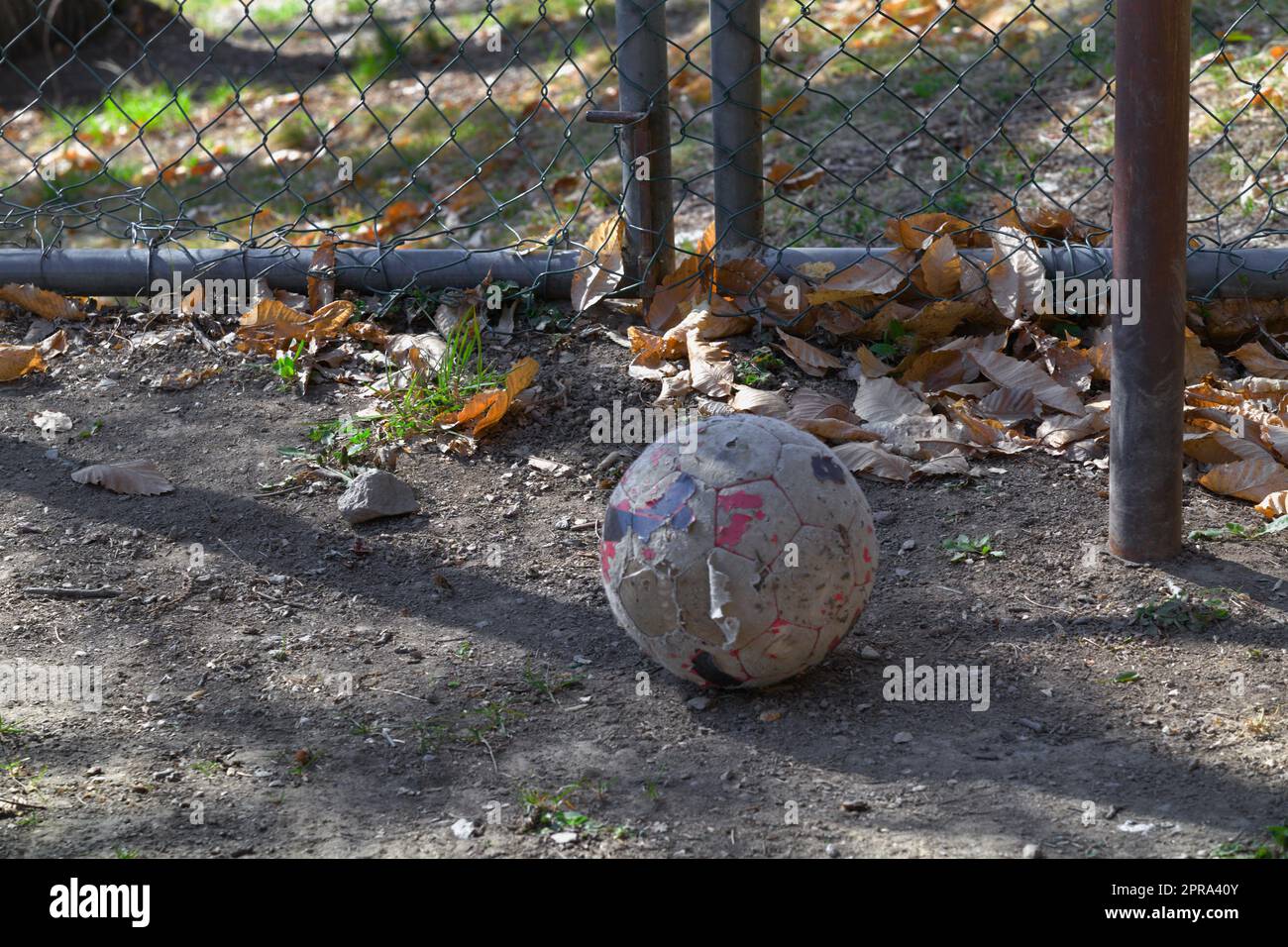 Vieux football sale sur l'aire de jeux abandonnée. Des parties de l'ancienne clôture, du poteau et de l'objectif sont visibles et montrent l'état abandonné de l'endroit. Banque D'Images