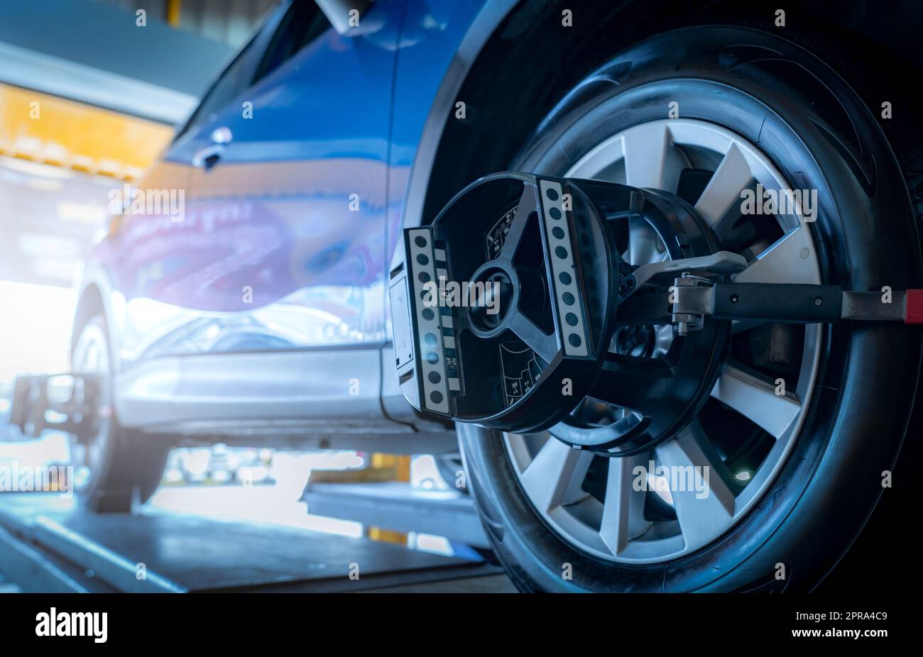 L'équipement de réglage de la géométrie des roues adhère au pneu de la roue de voiture dans l'atelier de réparation automobile. Alignement automatique des roues dans l'atelier de la station-service. Equilibre des roues de la voiture. Réglage de la suspension. Véhicule à l'intérieur de l'atelier de garage. Banque D'Images