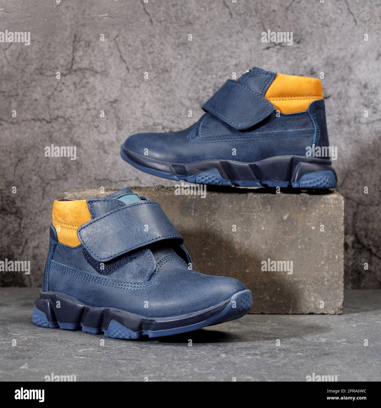 Chaussures de sport d'hiver bleues avec inserts orange et Velcro pour homme sur fond en béton gris. Banque D'Images