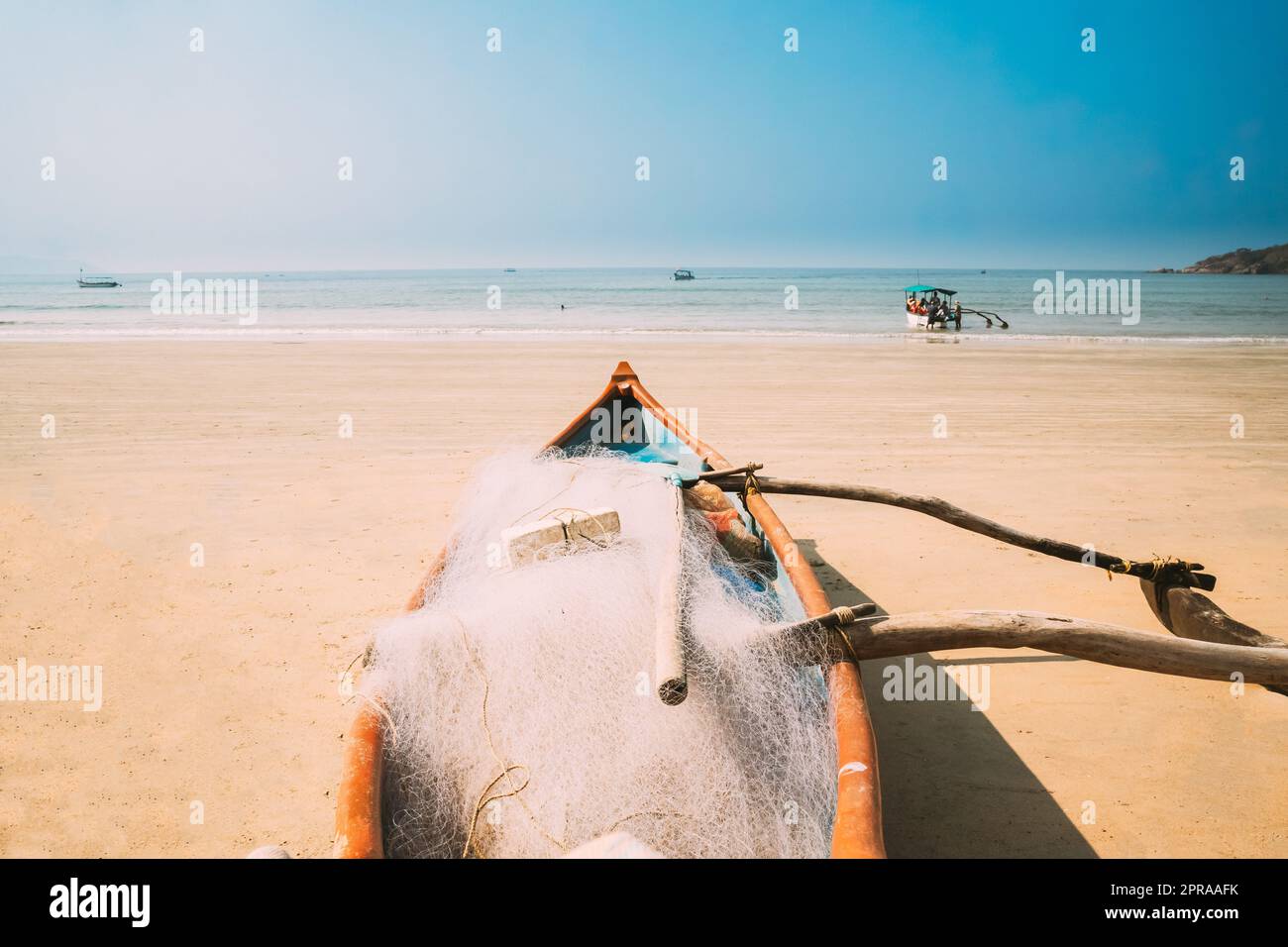 Canacona, Goa, Inde. Bateau de pêche en bois avec filet garé sur la célèbre plage de Palolem en été Sunny Day Banque D'Images