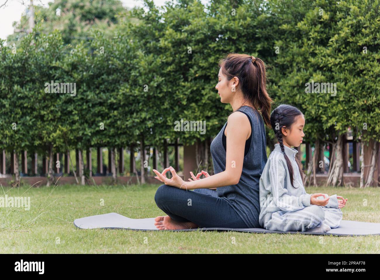 mère pratiquant des exercices de yoga avec sa fille à l'extérieur dans méditer poser ensemble Banque D'Images