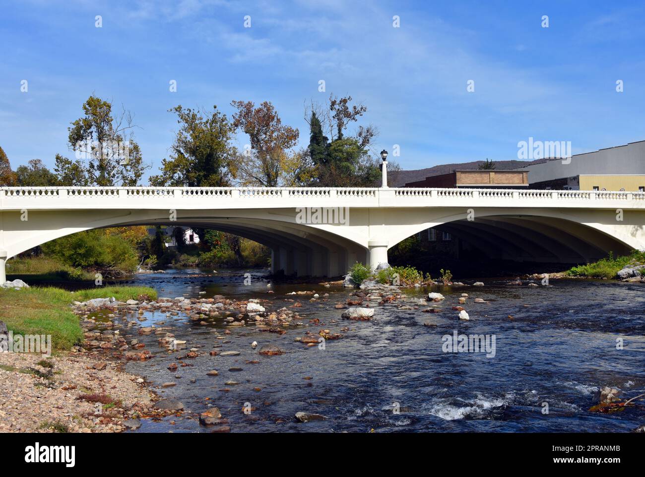 Elk Street Arch Bridge traverse la rivière Doe dans le centre-ville d'Elizabethton, Tennessee. Le pont est peint en blanc et est en béton. Le ciel est bleu. Banque D'Images