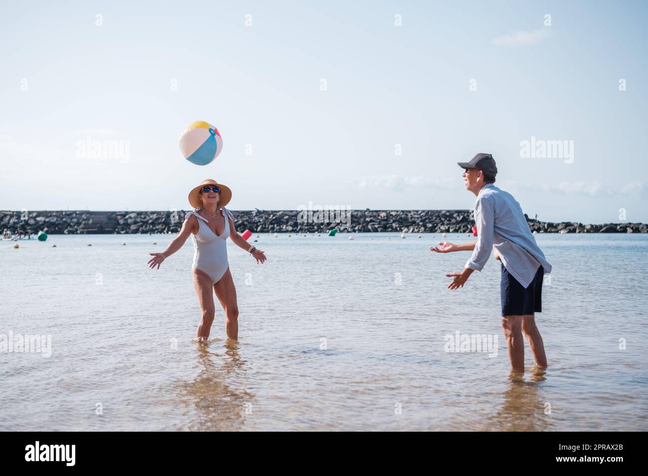 Deux personnes âgées jouant de la balle en plastique sur la plage et s'amusant et s'exerçant à leur retraite. concept: style de vie, retraite, sport Banque D'Images