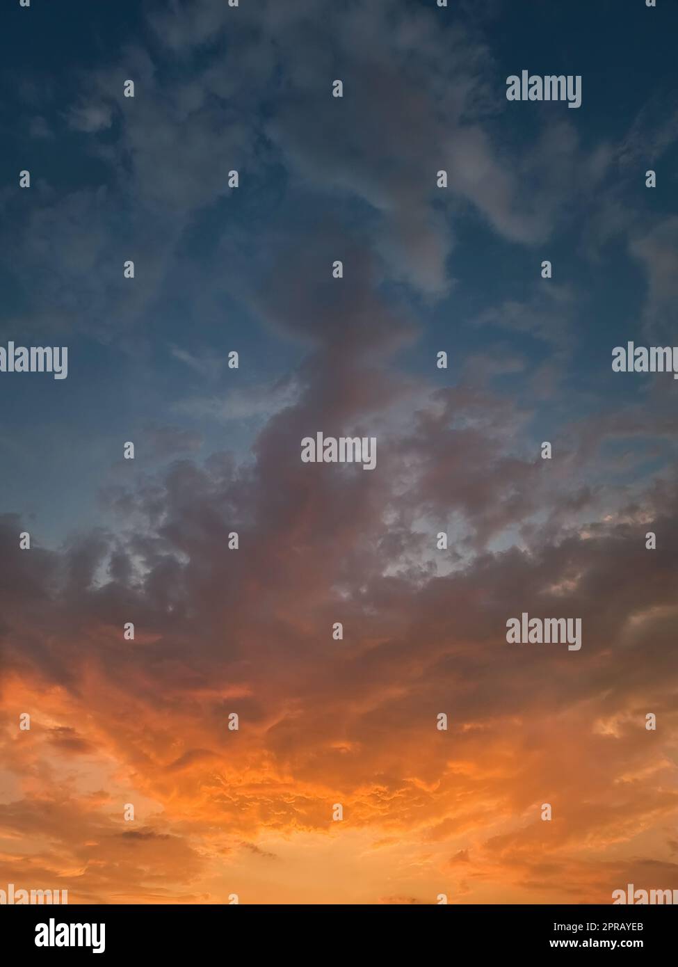 Magnifique ciel de coucher de soleil avec des nuages orange colorés au-dessus de l'horizon, fond céleste vertical Banque D'Images