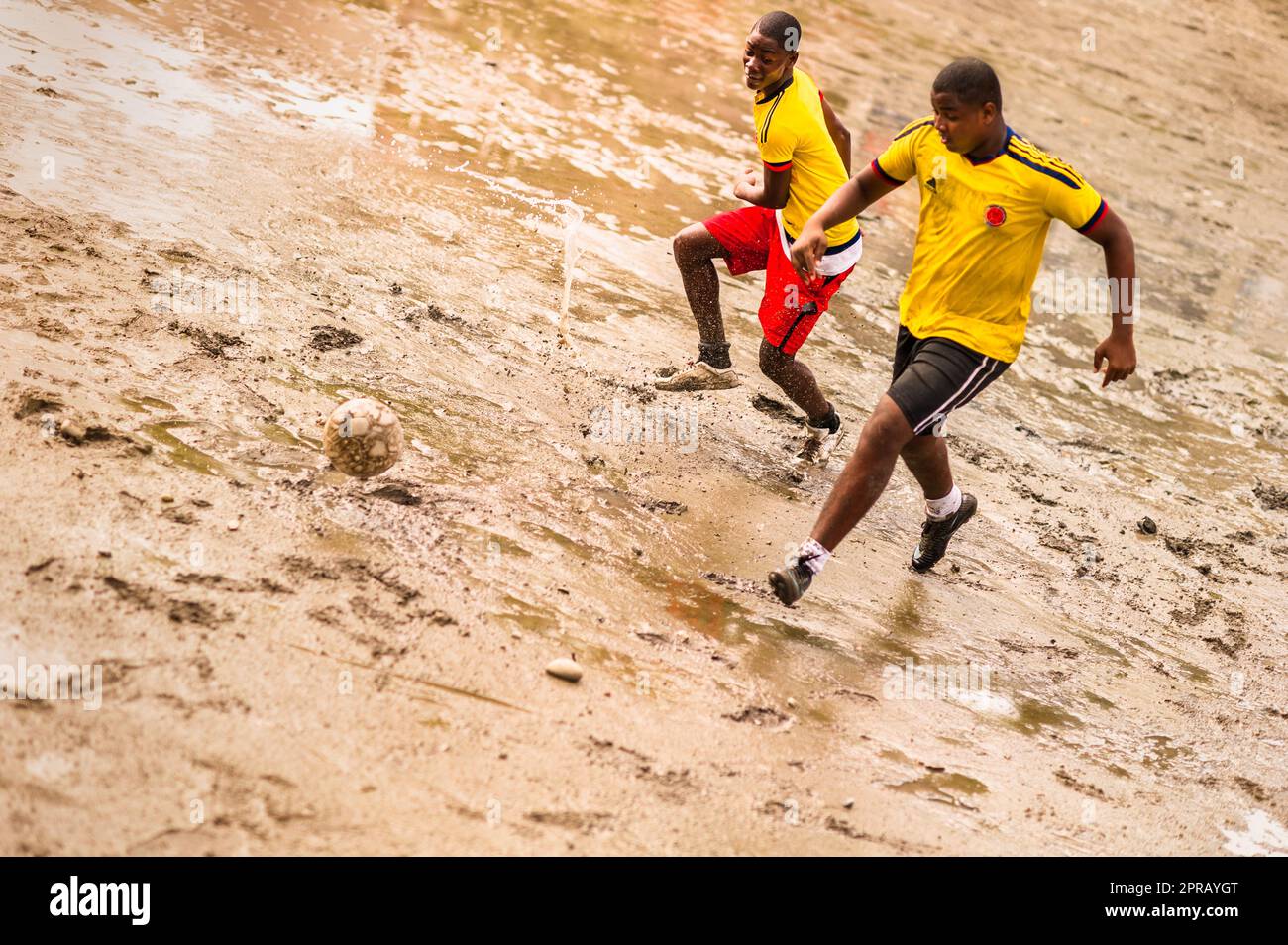 De jeunes joueurs de football afro-colombiens jouent un match lors d'une séance d'entraînement sur un terrain boueux à Quibdó, Chocó, Colombie. Banque D'Images