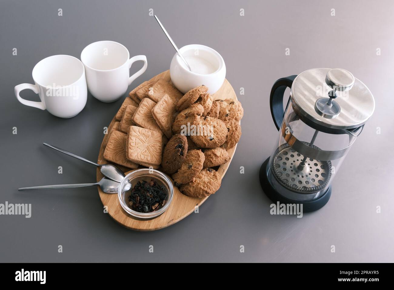 Un délicieux en-cas deux tasses de thé noir et une assiette de biscuits de flocons d'avoine une planche en bois sur fond gris, thé de feuilles. Banque D'Images