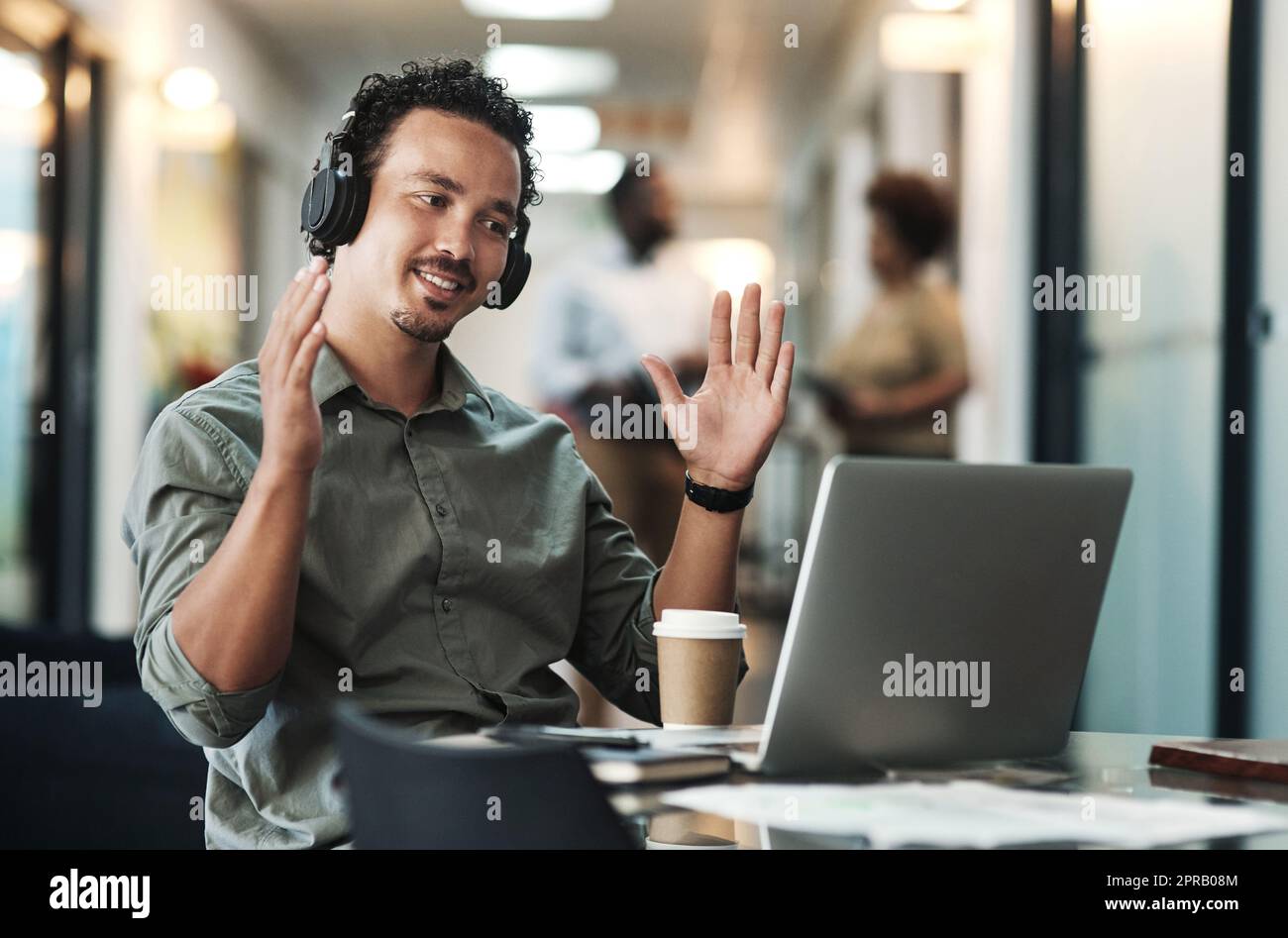 Je pense que nous pouvons nous développer de manière plus importante : un jeune homme d'affaires assis au bureau et portant des écouteurs tout en utilisant son ordinateur portable pour une réunion virtuelle. Banque D'Images