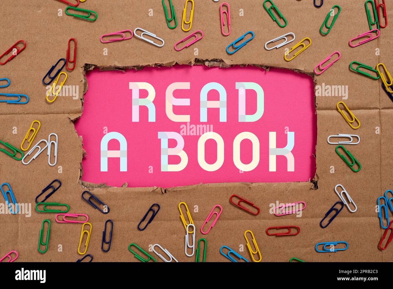 Signe écrit à la main Lire Un livre. Idée d'affaires appréciez la littérature activité traditionnelle Apprenez de nouvelles choses importantes idées écrites sous le carton déchiré avec des trombones autour. Banque D'Images