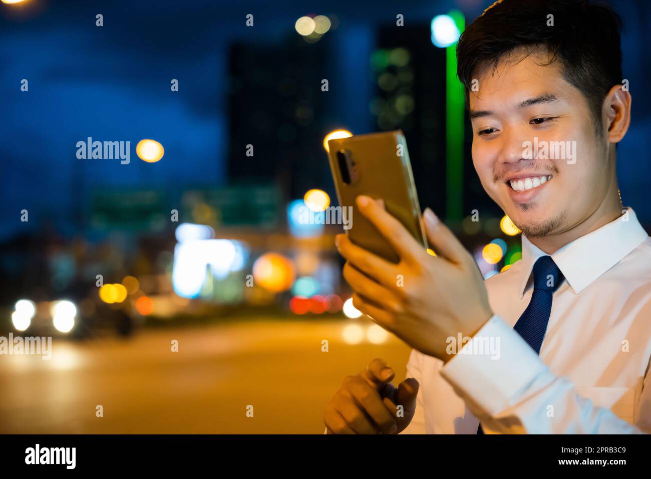 homme d'affaires saisissant un sms via smartphone après avoir travaillé près du bureau dans la rue nocturne de la ville Banque D'Images