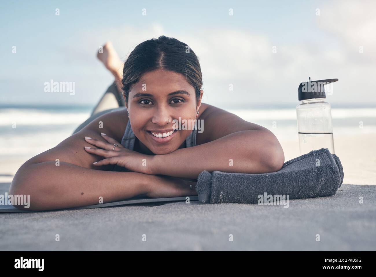 Le yoga est l'une de mes formes préférées d'exercice. Une jeune femme sportive qui s'étend sur son tapis de yoga à la plage. Banque D'Images