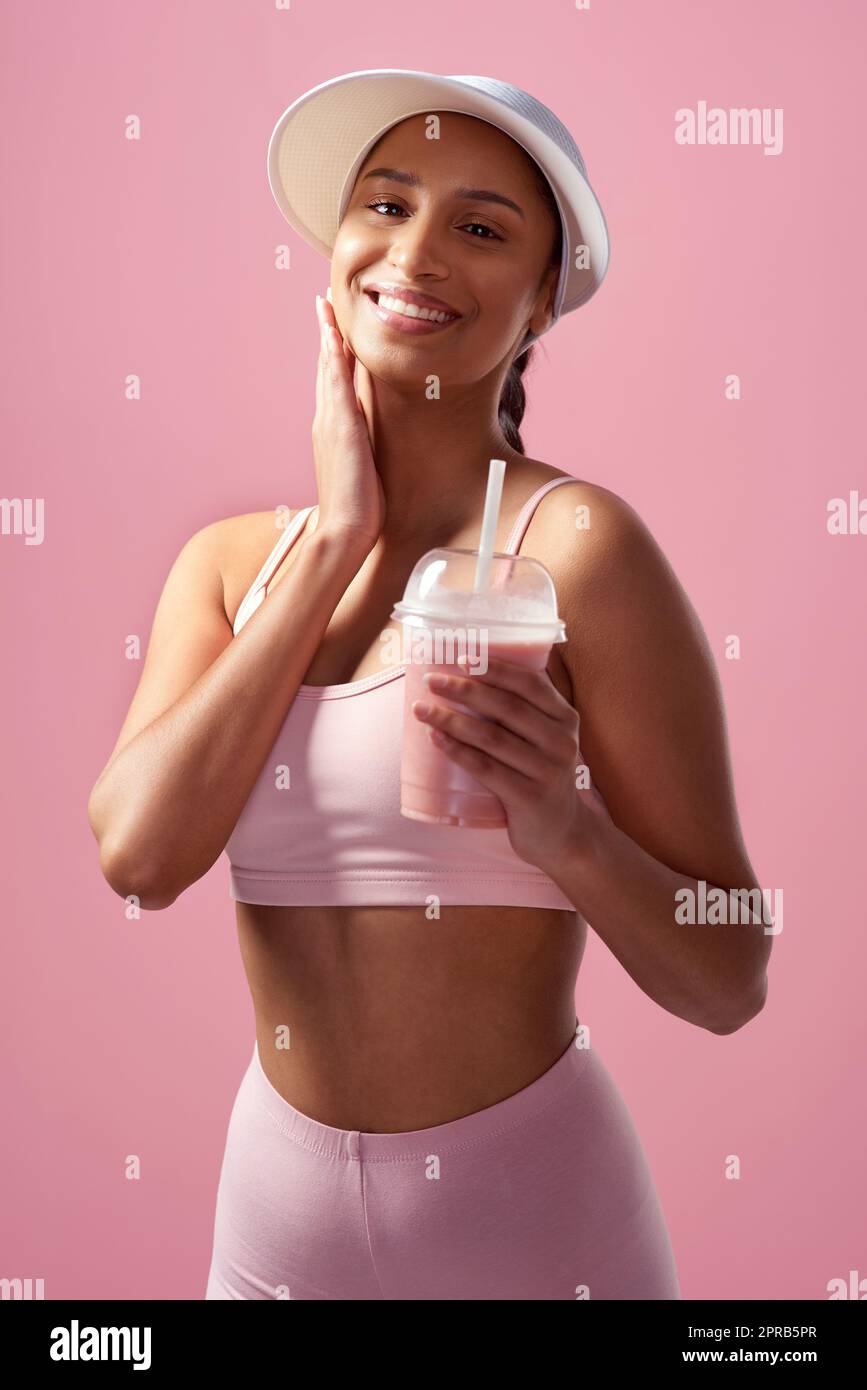 Le bonheur est à côté de la santé. Portrait court d'une jeune femme attrayante et sportive posant avec un smoothie en studio sur fond rose. Banque D'Images
