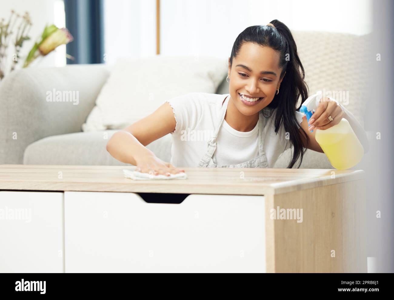 Désinfectez les surfaces vérifiées. Une jeune femme a l'air heureuse en faisant des tâches à la maison. Banque D'Images