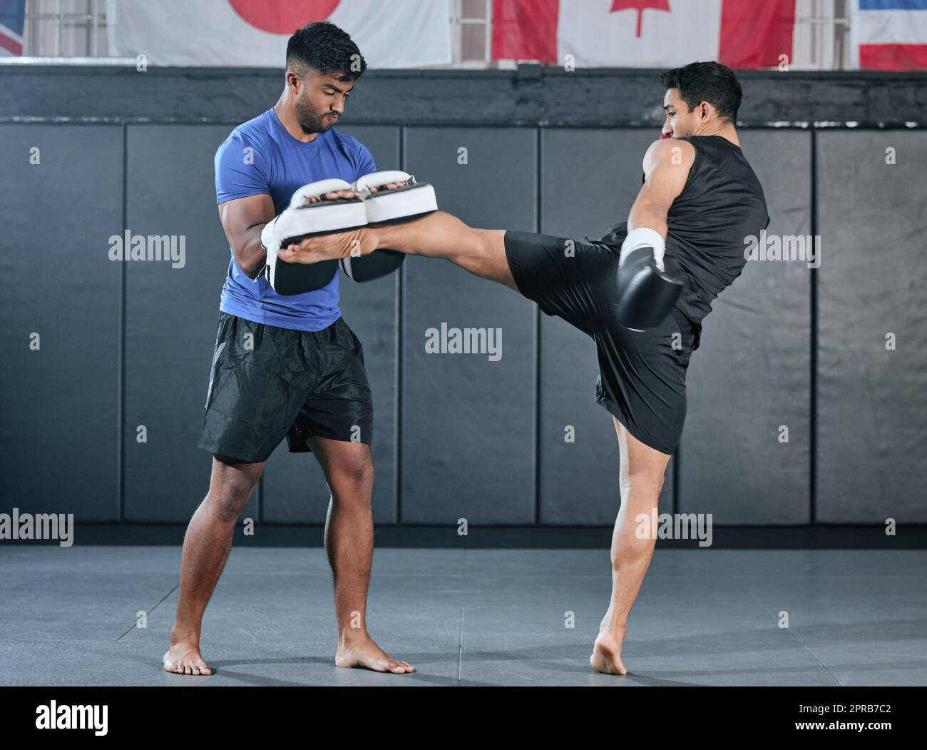 Active, athlètes et FIT hommes kick-boxing et faire des exercices d'entraînement sportif dans une salle de gym. Deux partenaires masculins ou MMA boxer et entraîneur pratique des exercices de sparring pour un style de vie sain de bien-être. Banque D'Images