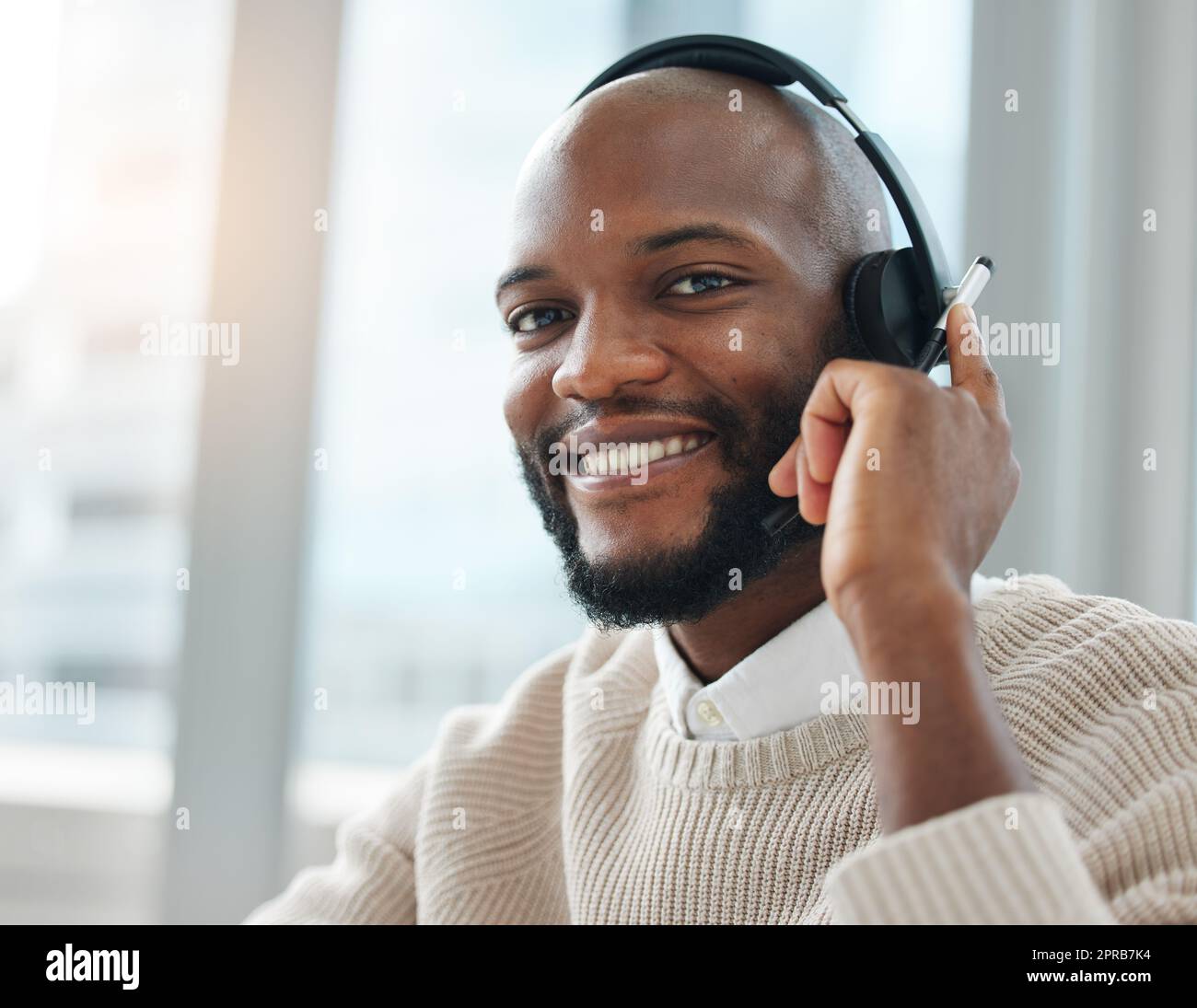 Redirigeant votre appel. Un jeune vendeur élégant assis seul dans son bureau et portant un casque. Banque D'Images