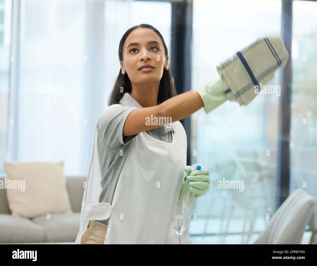 Essayer de garder mes fenêtres étincelantes propres. Une jeune femme nettoyant une surface de verre à la maison. Banque D'Images