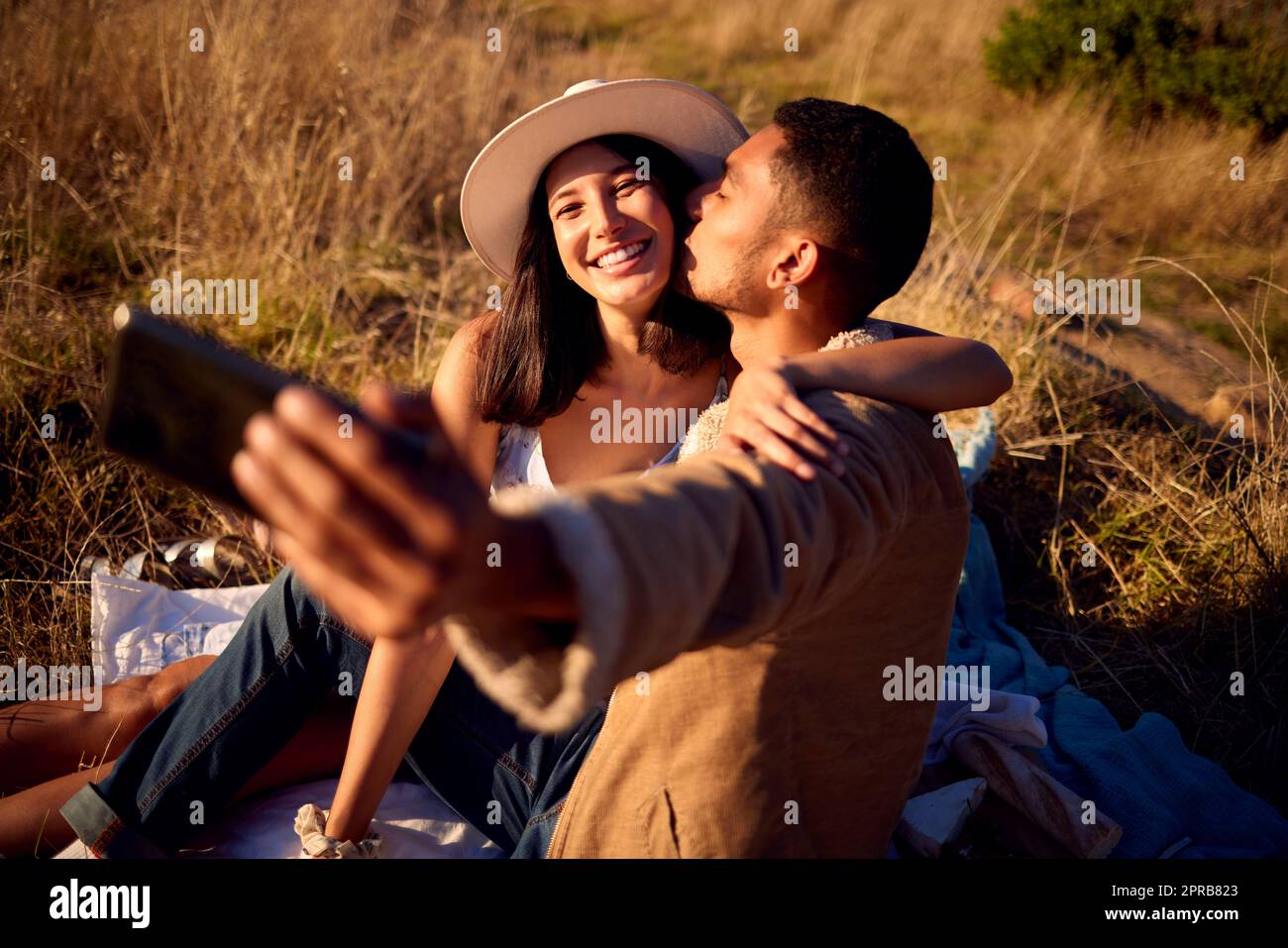 Immortalisez ce moment. Un jeune couple qui profite du coucher du soleil et prend un selfie dehors dans la nature. Banque D'Images