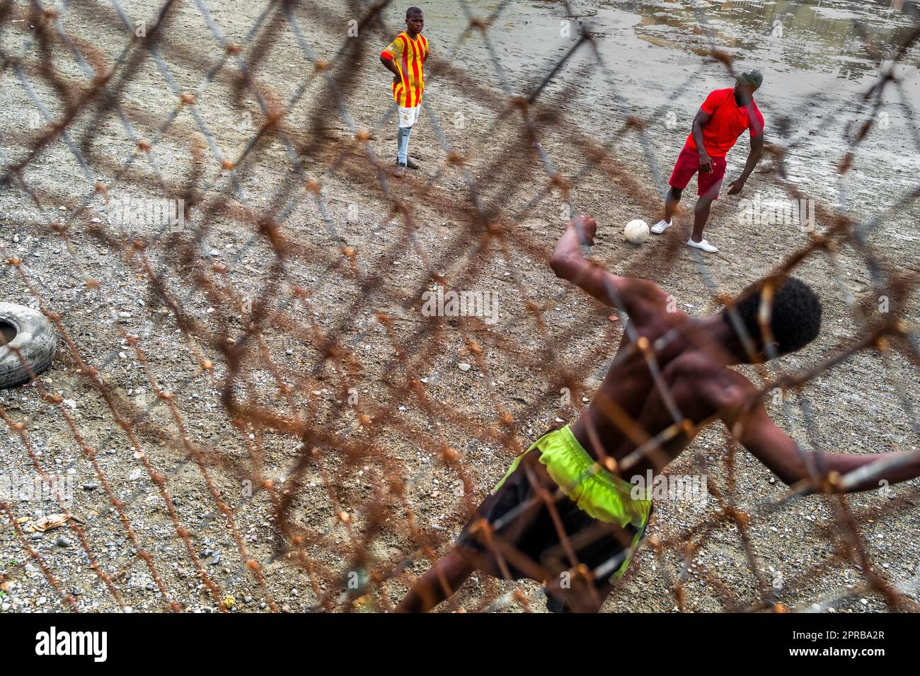 Un jeune joueur de football afro-colombien pratique le tir lors d'une session d'entraînement sur un terrain de jeu de terre à Quibdó, Chocó, Colombie. Banque D'Images