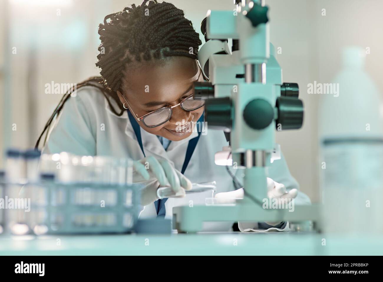 La science est un canal vital de connaissances. Un jeune scientifique utilisant un microscope dans un laboratoire. Banque D'Images