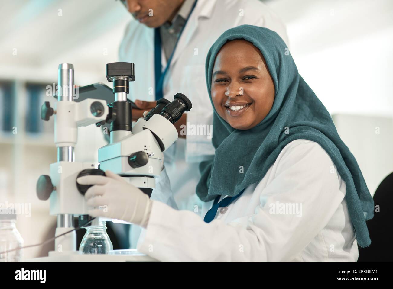 La science va tout résoudre. Portrait d'un jeune scientifique utilisant un microscope tout en travaillant avec un collègue dans un laboratoire. Banque D'Images
