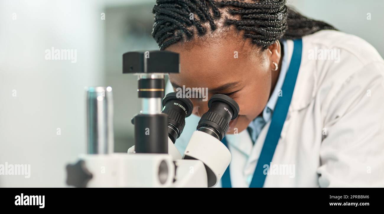 Déballage du fonctionnement du monde un jeune scientifique utilisant un microscope dans un laboratoire. Banque D'Images