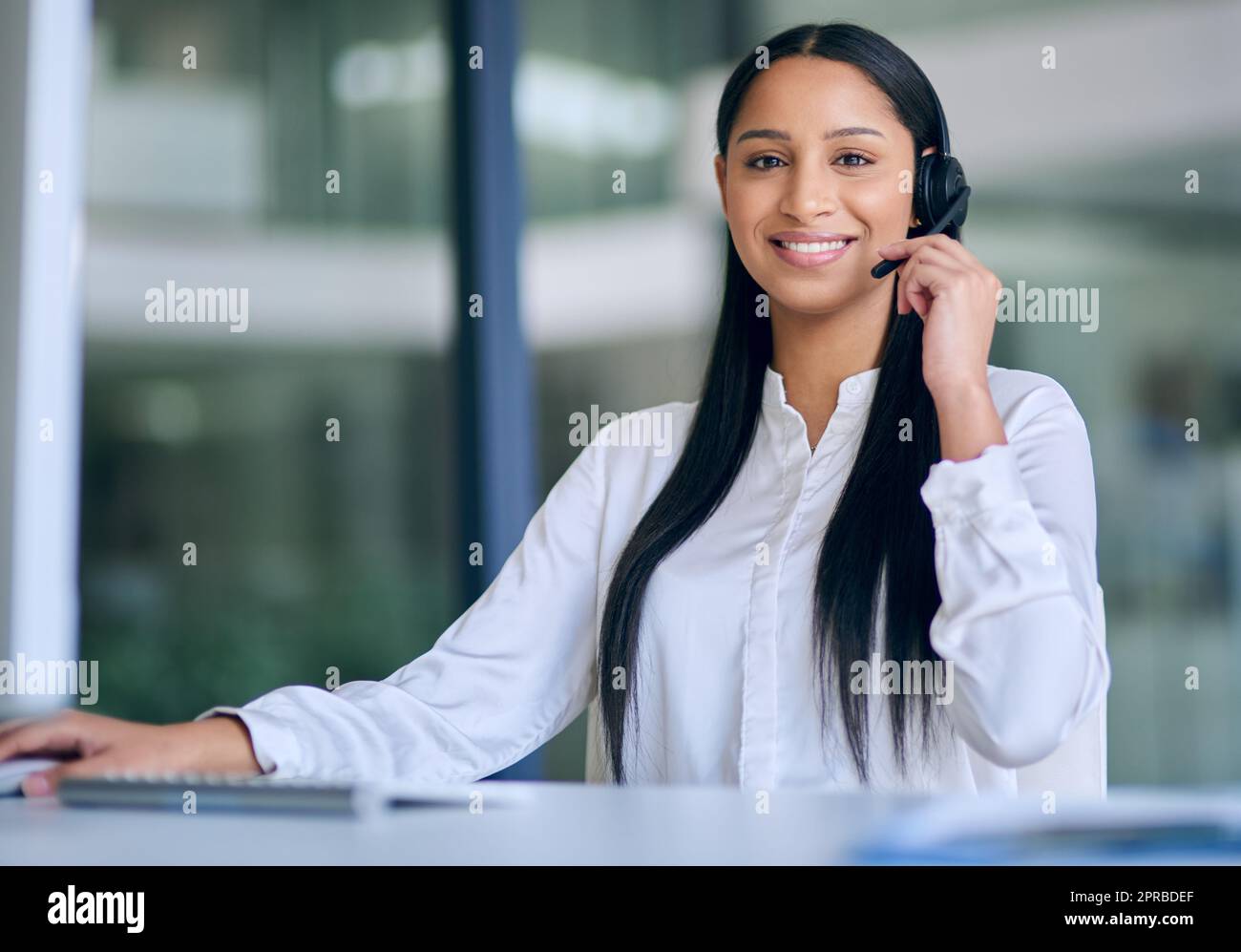 Nos clients sont au cœur de notre organisation : une jeune femme utilisant un micro-casque et un ordinateur dans un bureau moderne. Banque D'Images