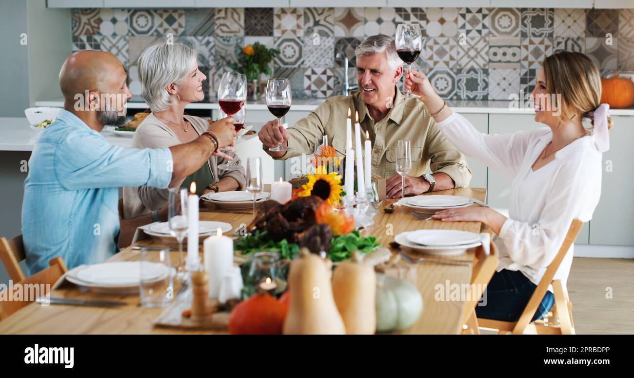 Des amis comme vous sont spéciaux tous les jours de l'année. Deux couples heureux assis pour le déjeuner et toaster avec des verres à vin à la maison. Banque D'Images