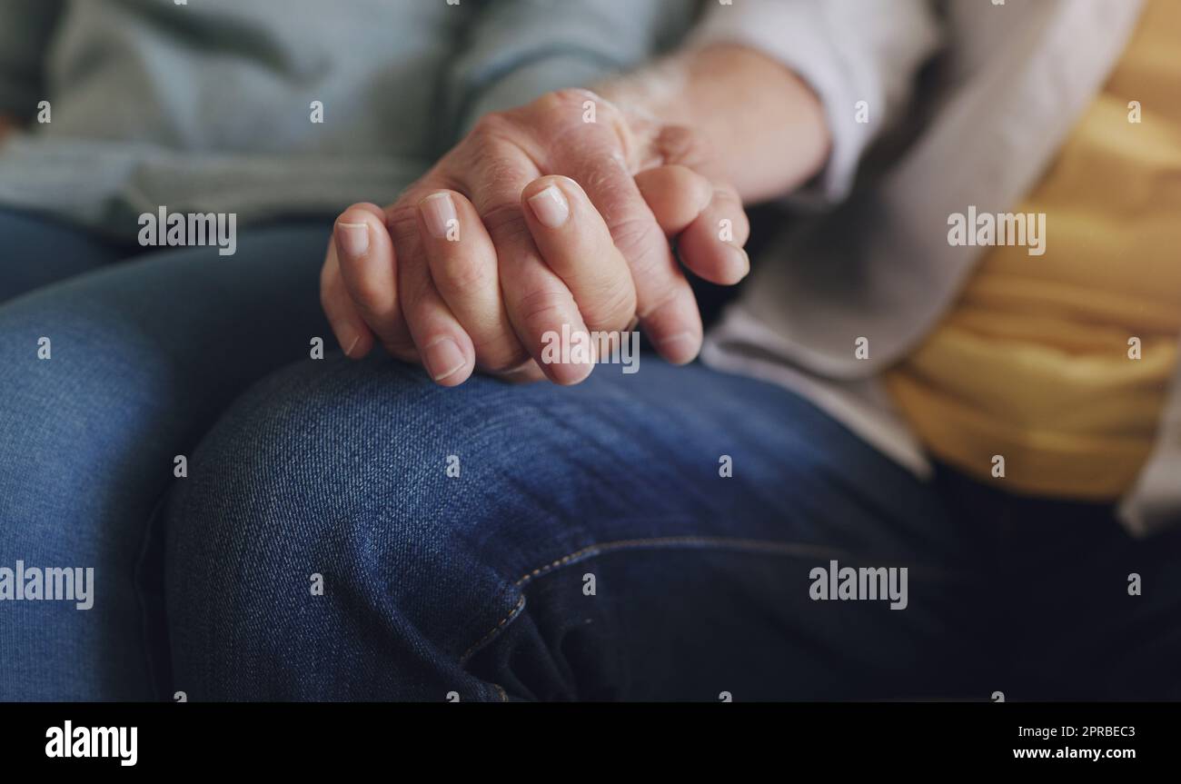 Nous nous sommes engagés à passer pour toujours ensemble, un couple méconnaissable assis dans leur salon et tenant les mains. Banque D'Images