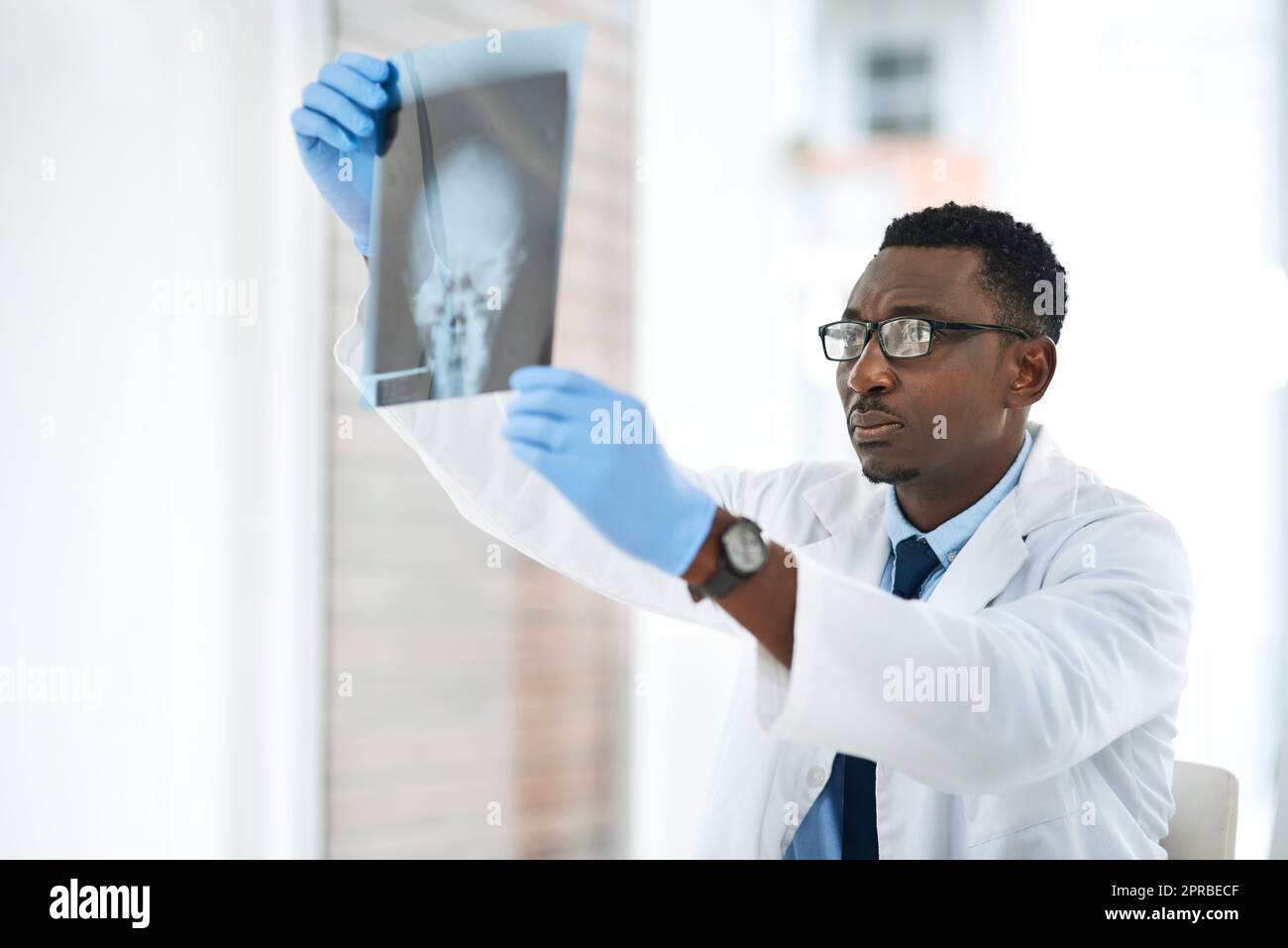 Vers une merveille médicale. Un jeune médecin analysant une radiographie du crâne d'un patient. Banque D'Images