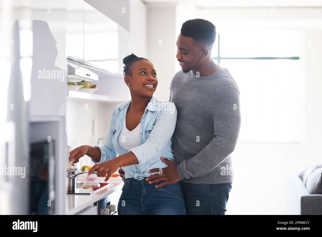 Je vous prépare votre favori. Un homme embrassant sa femme de derrière tout en hurle à cuisiner. Banque D'Images